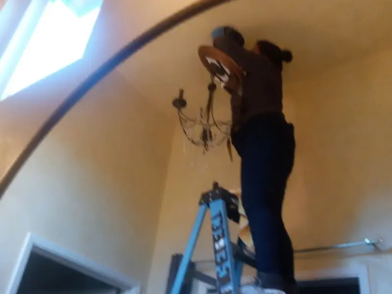 Electrician installing a chandelier in a Calcutta residence